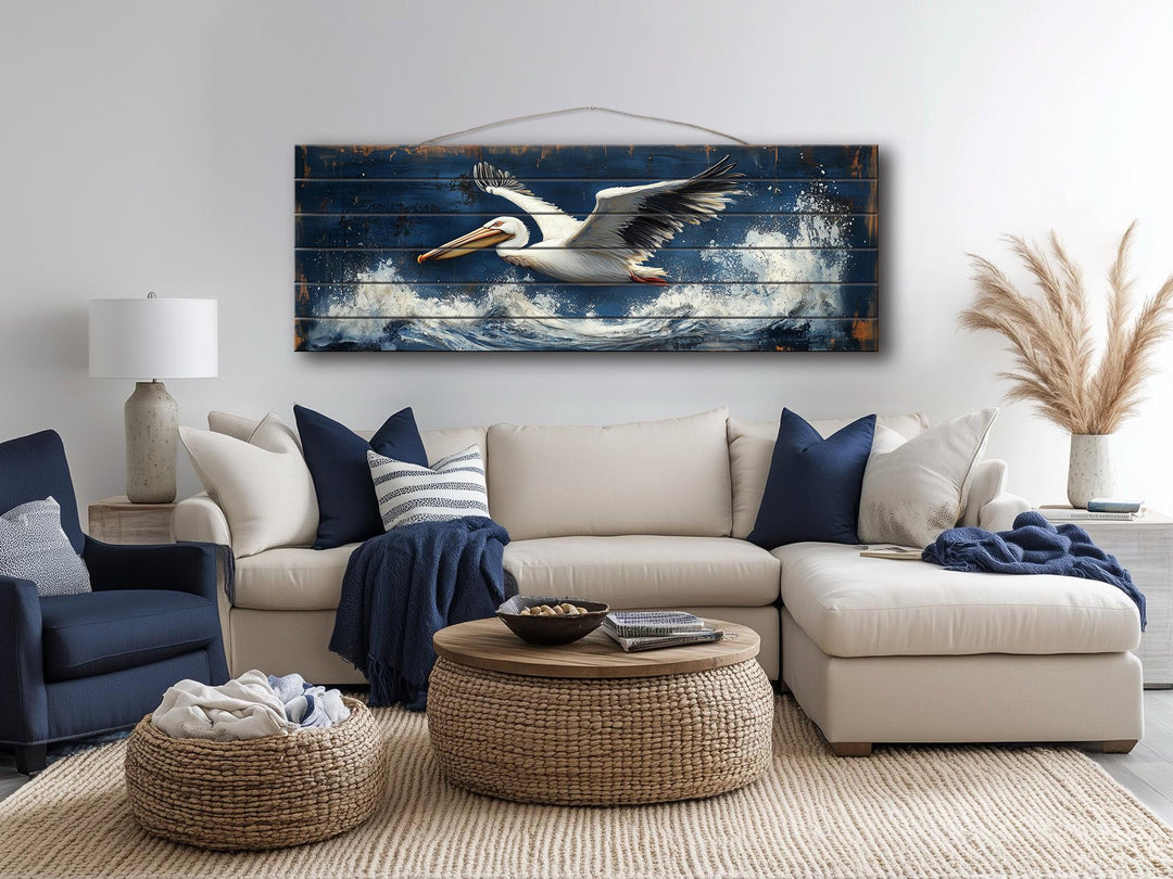 Long horizontal nautical wall art of a pelican flying over ocean waves on distressed wood.