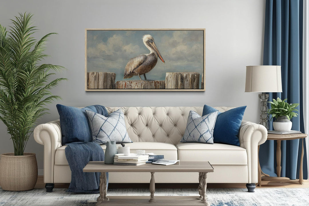 Pelican standing on wooden posts coastal canvas wall art displayed above a sofa in a living room.