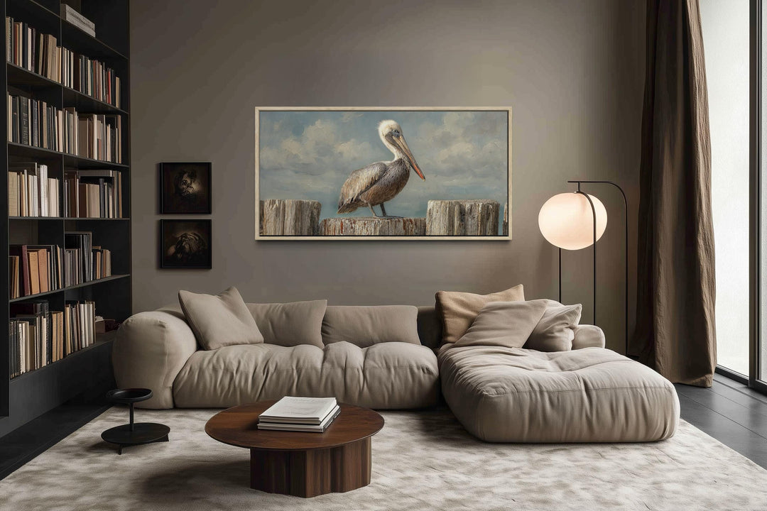Horizontal coastal canvas wall art of a pelican on wooden posts in a modern living room.