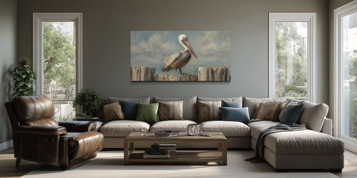 Horizontal coastal canvas wall art of a pelican on wooden posts above a modern sectional sofa.