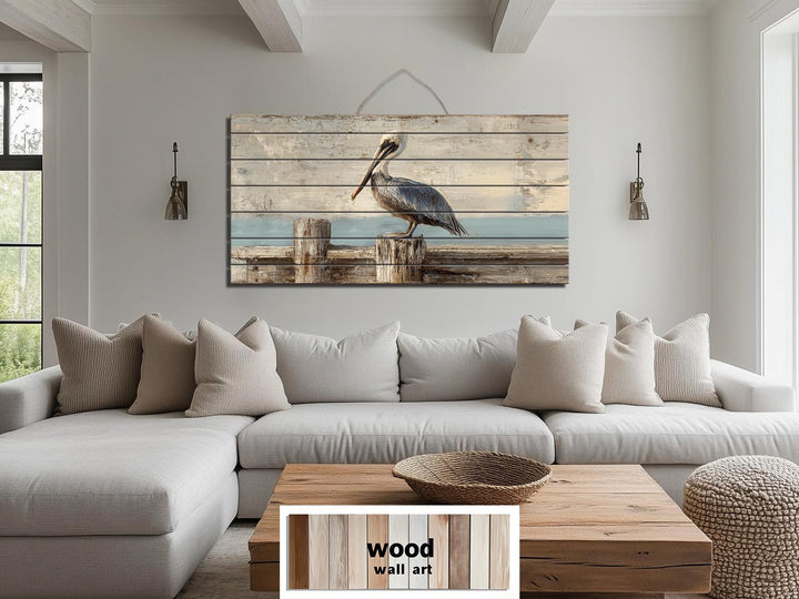 Pelican on a wooden dock coastal wall art printed on distressed wood planks above a sofa.
