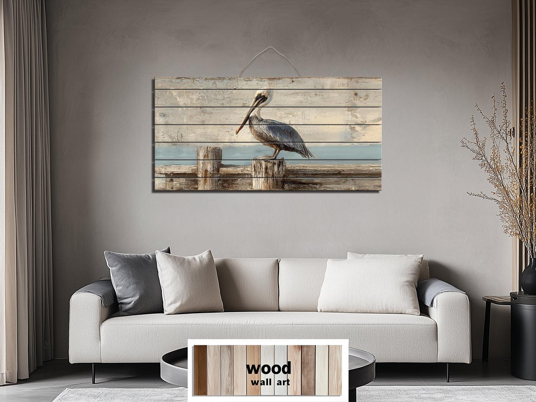 Pelican on a wooden dock coastal wall art print on distressed wood planks above a modern sofa.