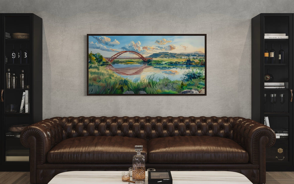 Pennybacker Bridge watercolor painting of Austin, Texas, framed above a brown leather sofa.