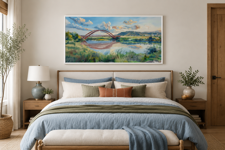 Pennybacker Bridge watercolor painting in a white frame hanging above a bed in a modern bedroom.