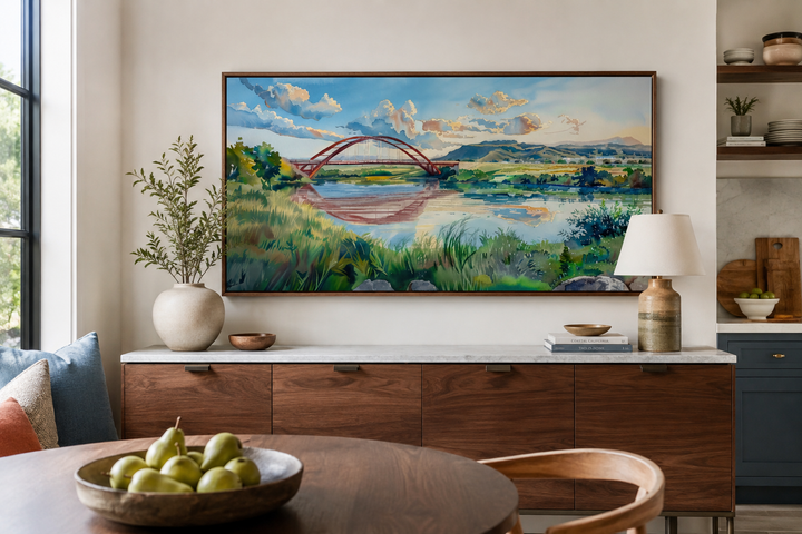 Watercolor painting of Pennybacker Bridge in Austin, Texas, framed and hung above a wooden sideboard.