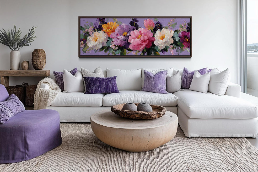 A long horizontal canvas print of vibrant purple and pink peonies hangs above a white sectional sofa.