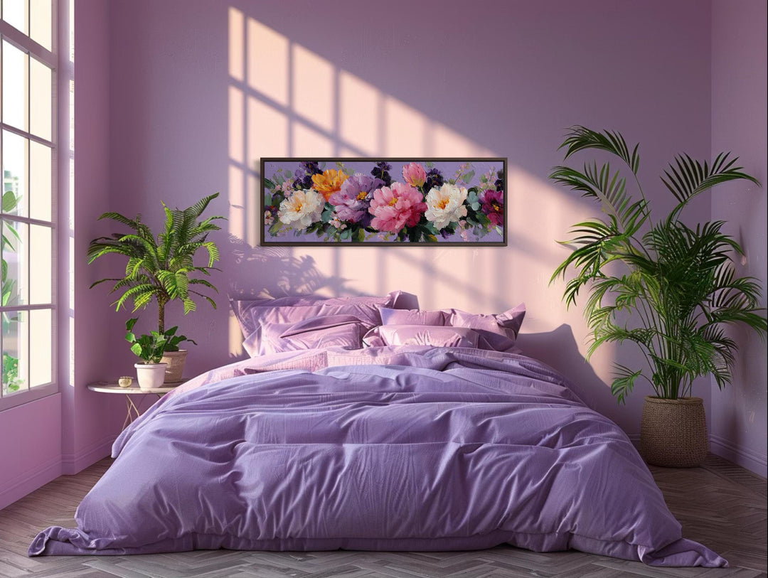 A long horizontal canvas painting of colorful peonies hangs above a purple bed in a sunlit room.