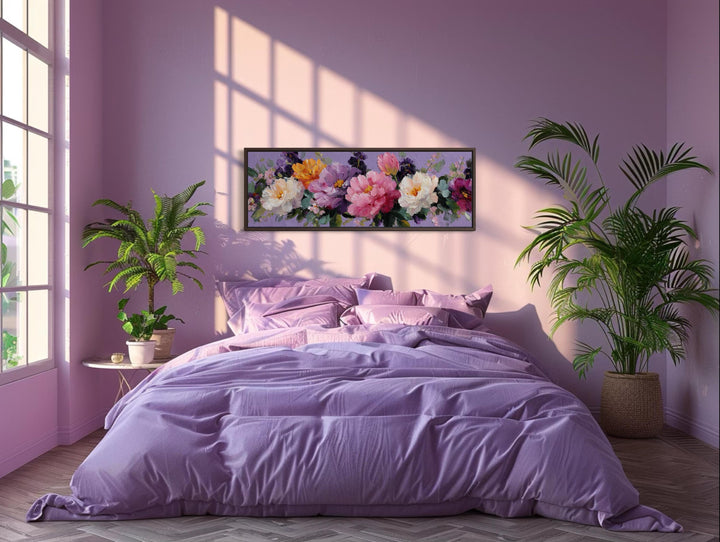 A long horizontal canvas painting of colorful peonies hangs above a purple bed in a sunlit room.