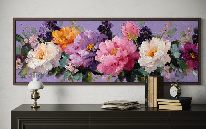 A long horizontal canvas painting of vibrant peonies in pink, purple, and white on a purple wall.