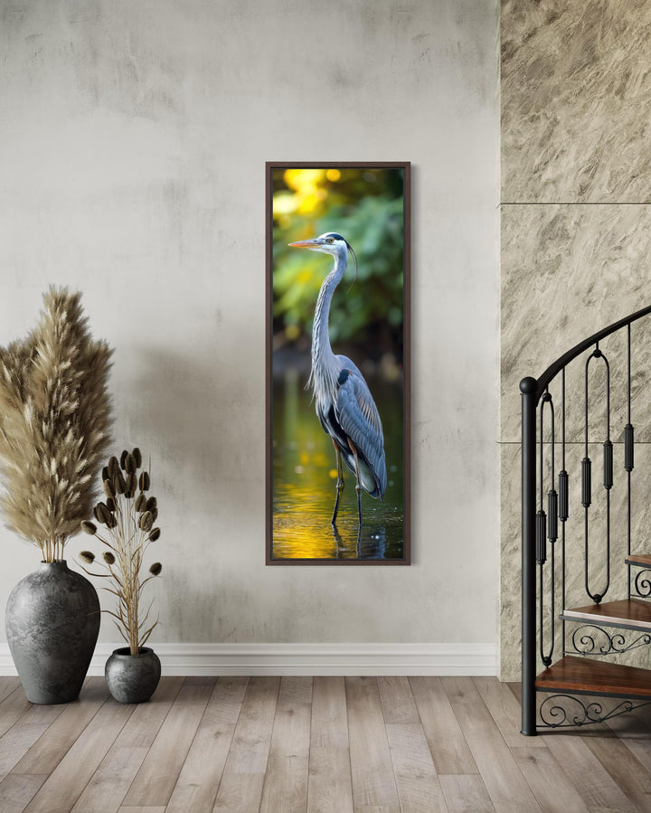 Vertical narrow wall art of a blue heron standing in water, framed in a modern interior setting.