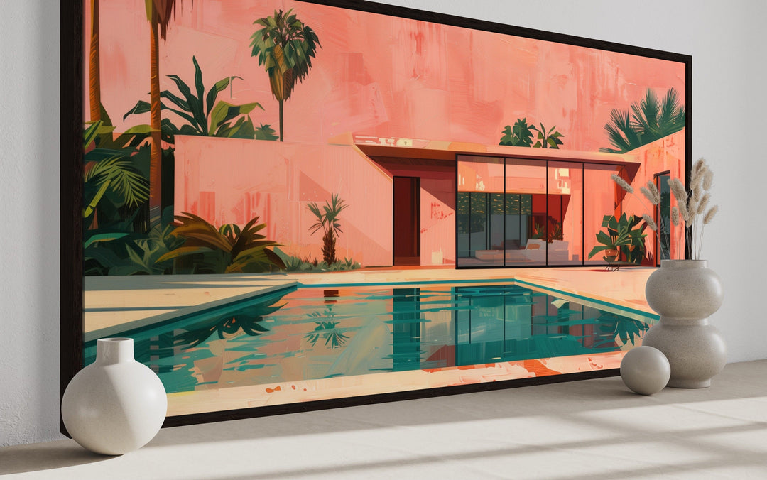Framed mid-century modern canvas print of a pink house and pool with palm trees in a room setting.
