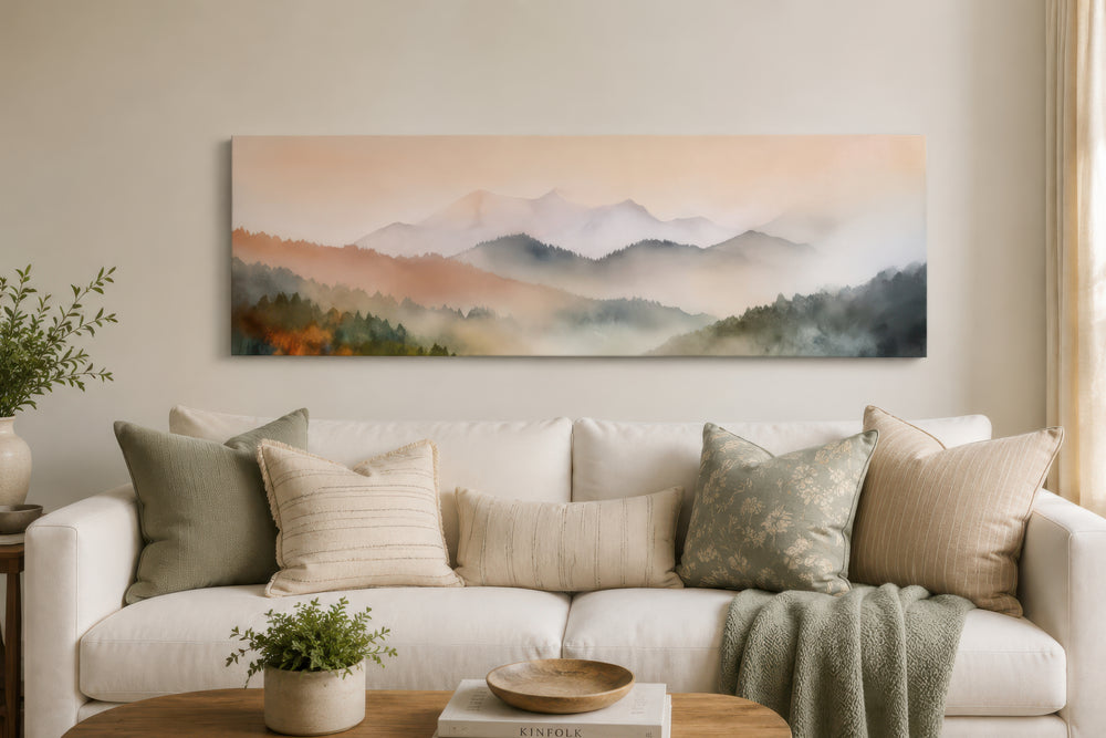 A wide canvas print of a pink and green pastel mountain landscape hangs above a white sofa.