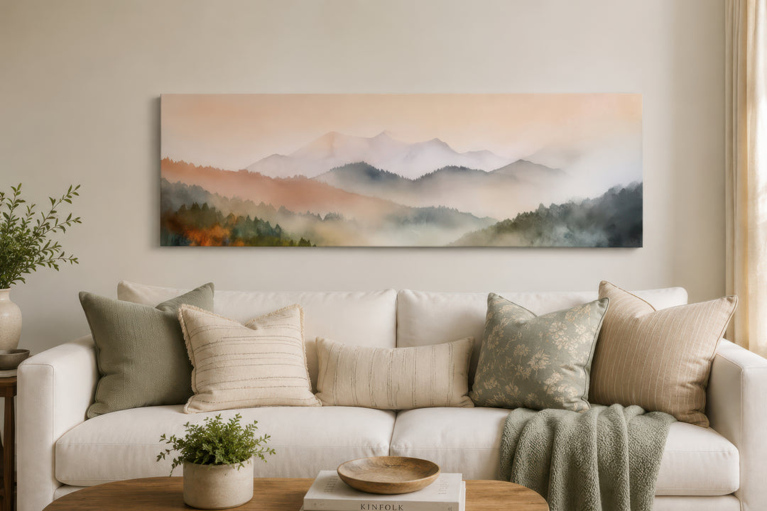 A wide canvas print of a pink and green pastel mountain landscape hangs above a white sofa.