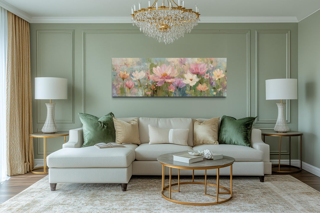 A long horizontal canvas painting of pink and white flowers hangs above a sofa in a green room.