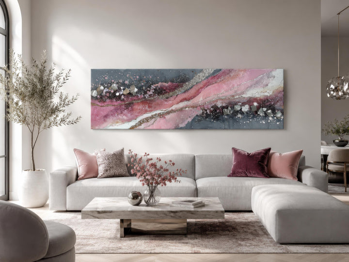 Long horizontal pink and grey geode-inspired abstract canvas print above a modern grey sofa.
