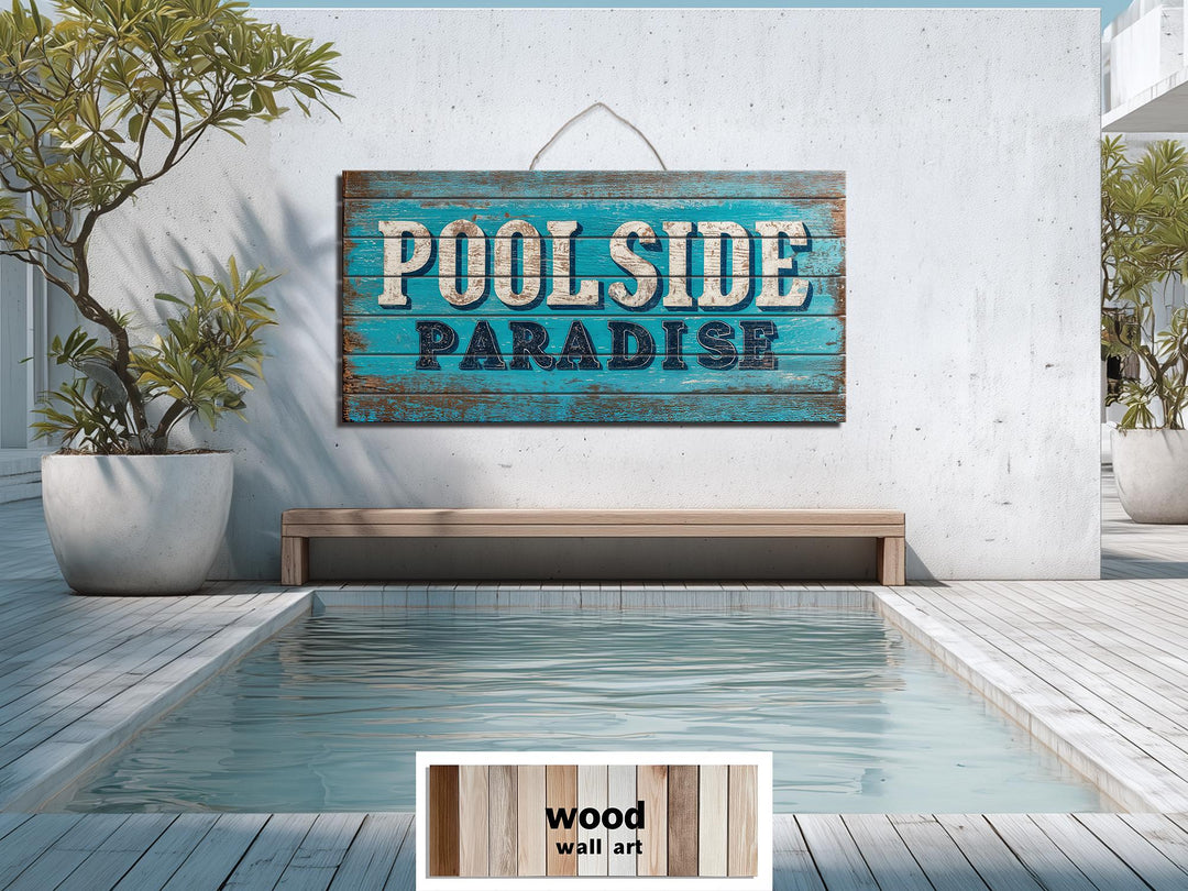 A rustic wood wall art sign reading Poolside Paradise hangs on a white wall above a swimming pool.