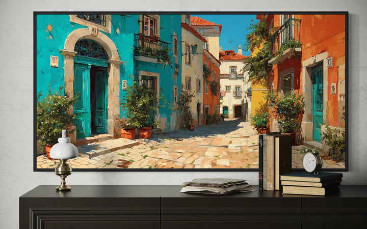 Portugal Street Scene Framed Canvas Wall Art above a dark dresser with books and a lamp.
