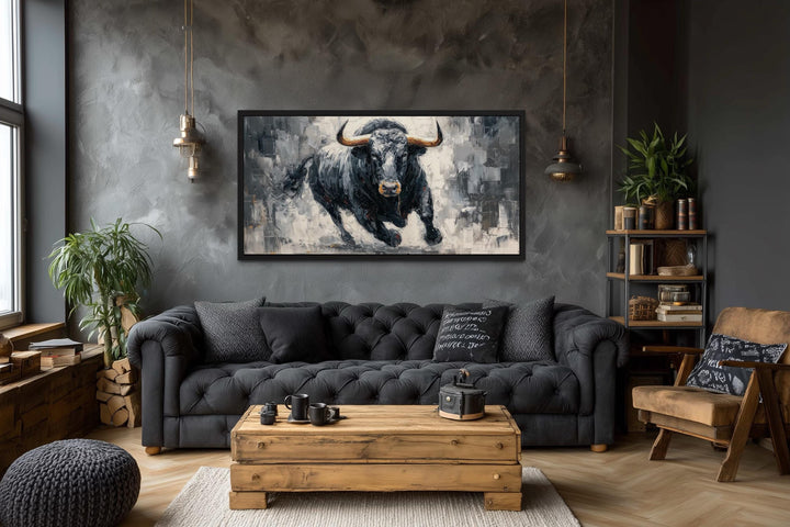 Charging Black Bull canvas wall art in a black frame above a dark grey tufted sofa in a modern room.