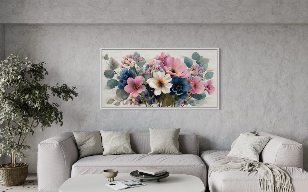 Pretty blue and pink wildflowers bouquet framed canvas wall art hanging above a modern grey sofa.