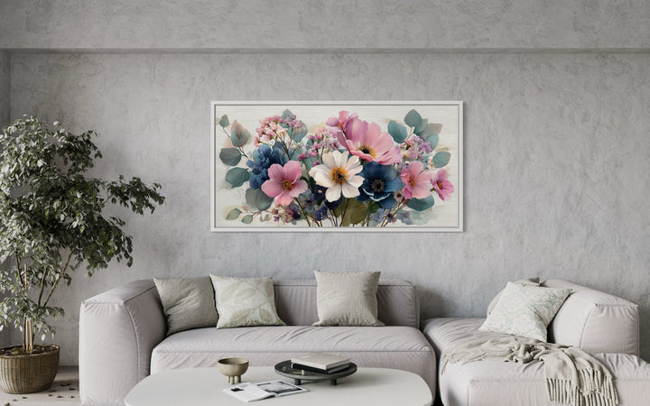 Pretty blue and pink wildflowers bouquet framed canvas wall art hanging above a modern grey sofa.