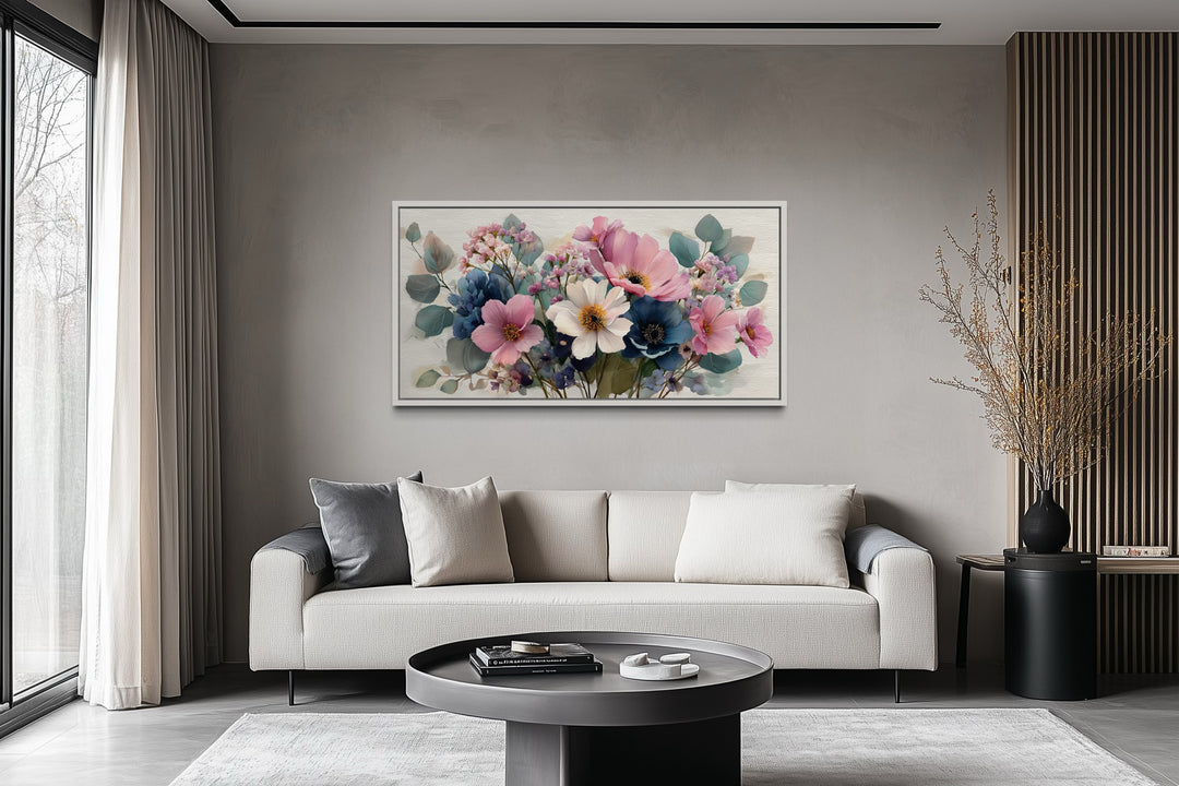 Horizontal framed canvas wall art of a blue and pink wildflower bouquet above a modern sofa.