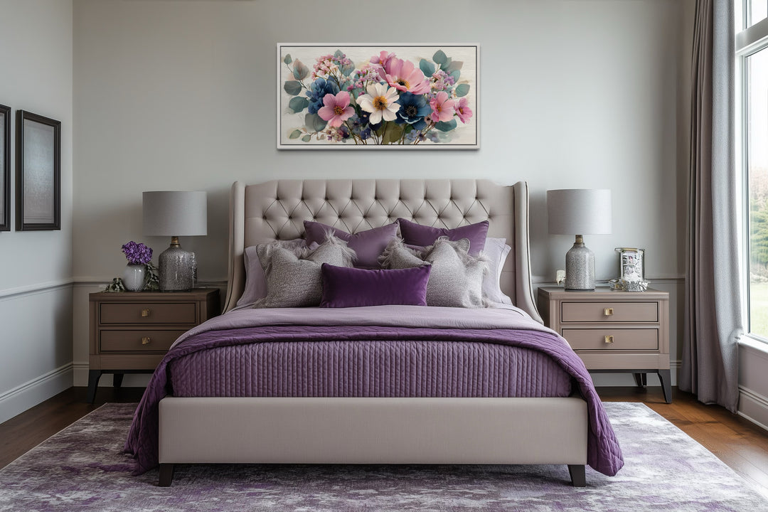 Pretty blue and pink wildflowers bouquet framed canvas wall art hanging above a tufted bed.