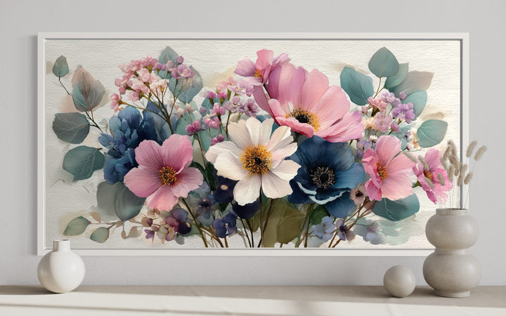 Pretty blue and pink wildflower bouquet framed canvas wall art displayed above a neutral shelf.