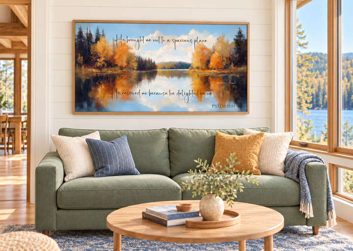 Psalm 18:19 scripture canvas art featuring an autumn lake painting above a green sofa.