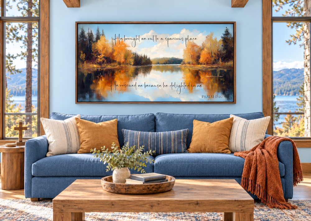 Psalm 18:19 canvas art featuring an autumn lake painting above a blue sofa in a bright living room.