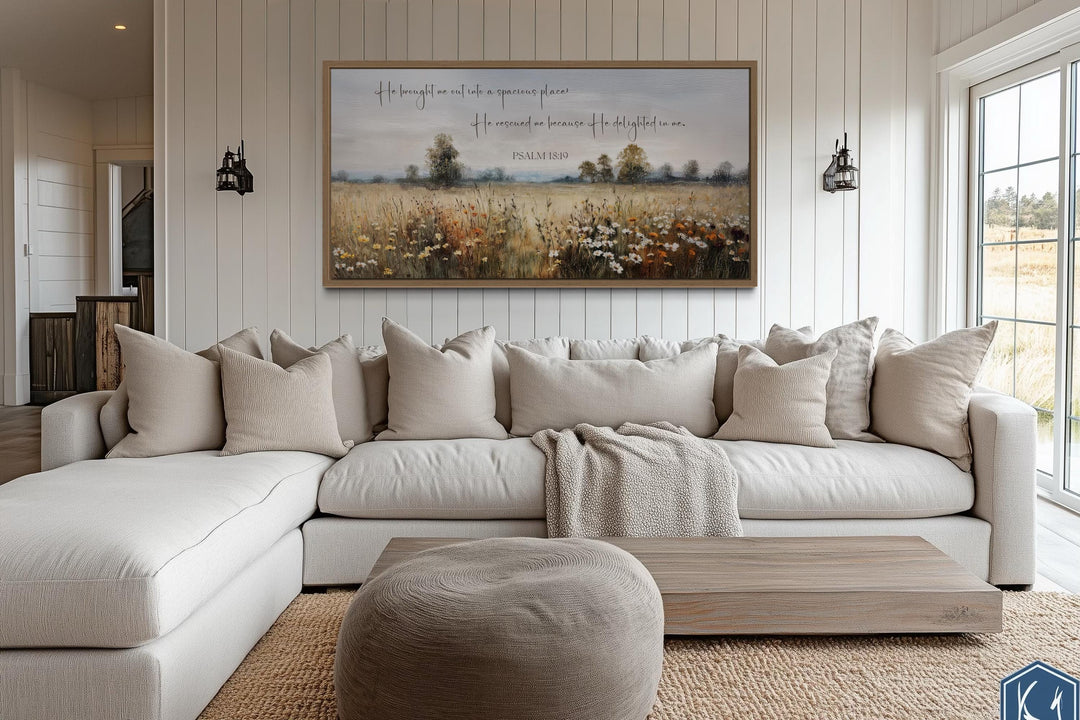 Psalm 18:19 scripture wall art on a wildflower field canvas above a neutral sectional sofa.
