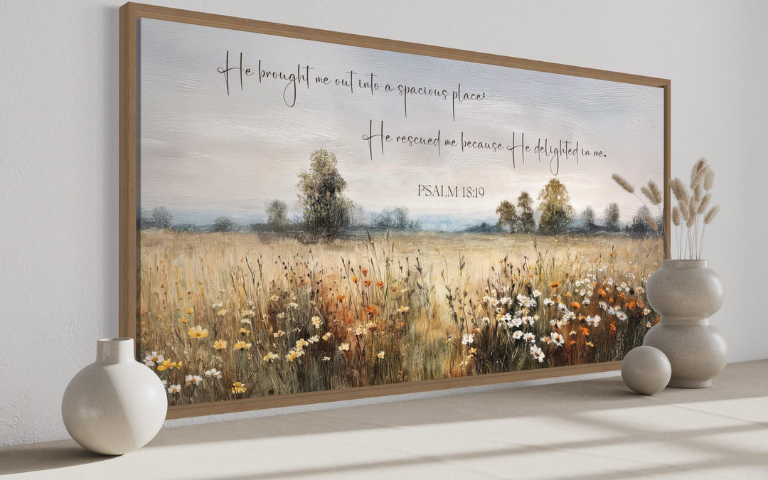 Psalm 18:19 scripture on a framed canvas featuring a painterly wildflower field and misty horizon.
