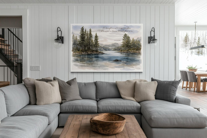 A serene lake landscape canvas print with Psalm 18:19 hangs above a gray sectional sofa.