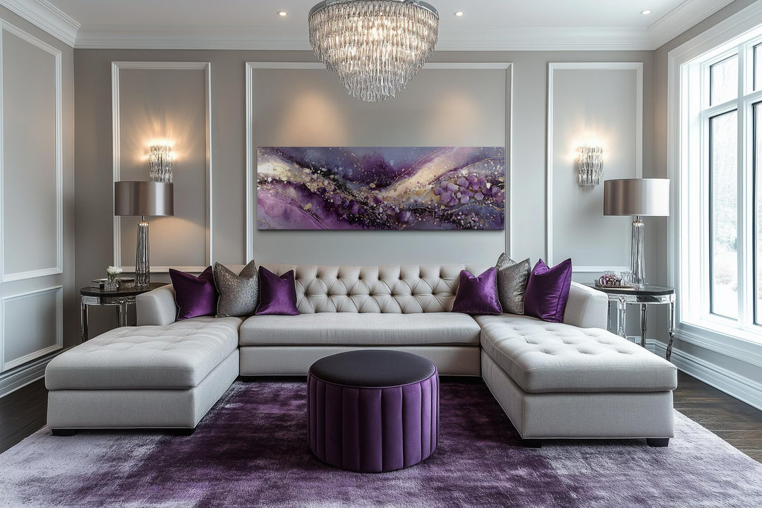 Horizontal purple and gold abstract canvas art centered above a tufted sofa in a luxury living room.