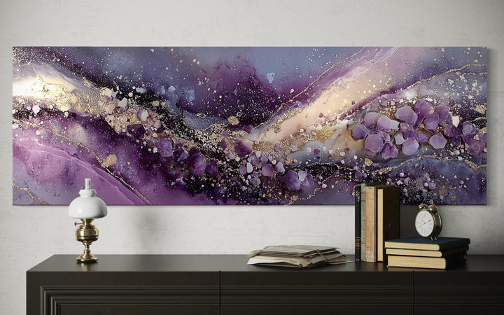 Purple abstract fluid landscape canvas print with gold accents displayed above a dark sideboard.