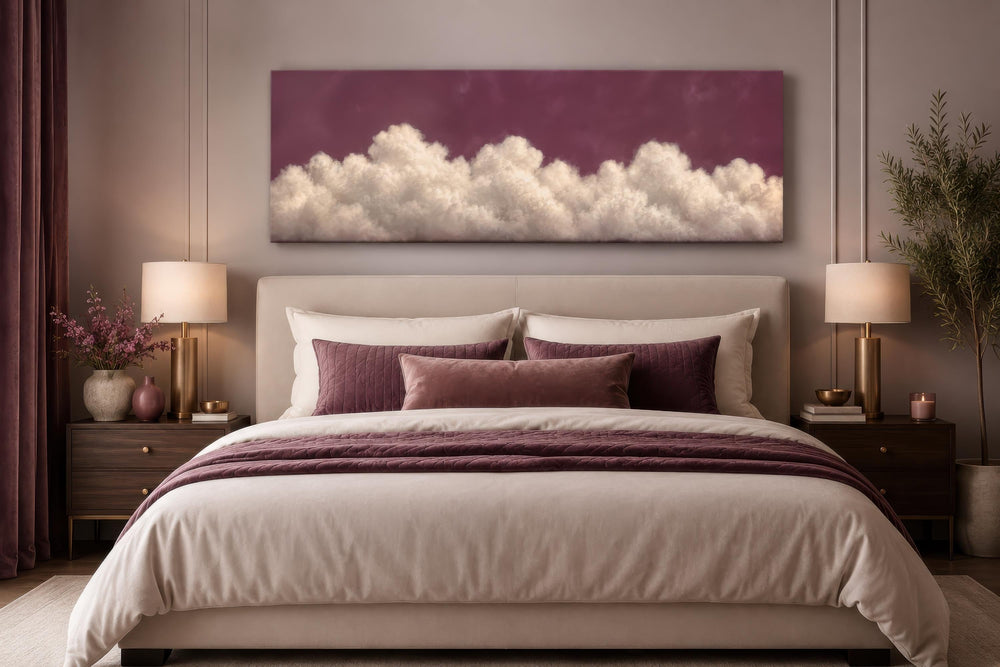 Long narrow canvas print of white fluffy clouds on a purple background above a bed headboard.