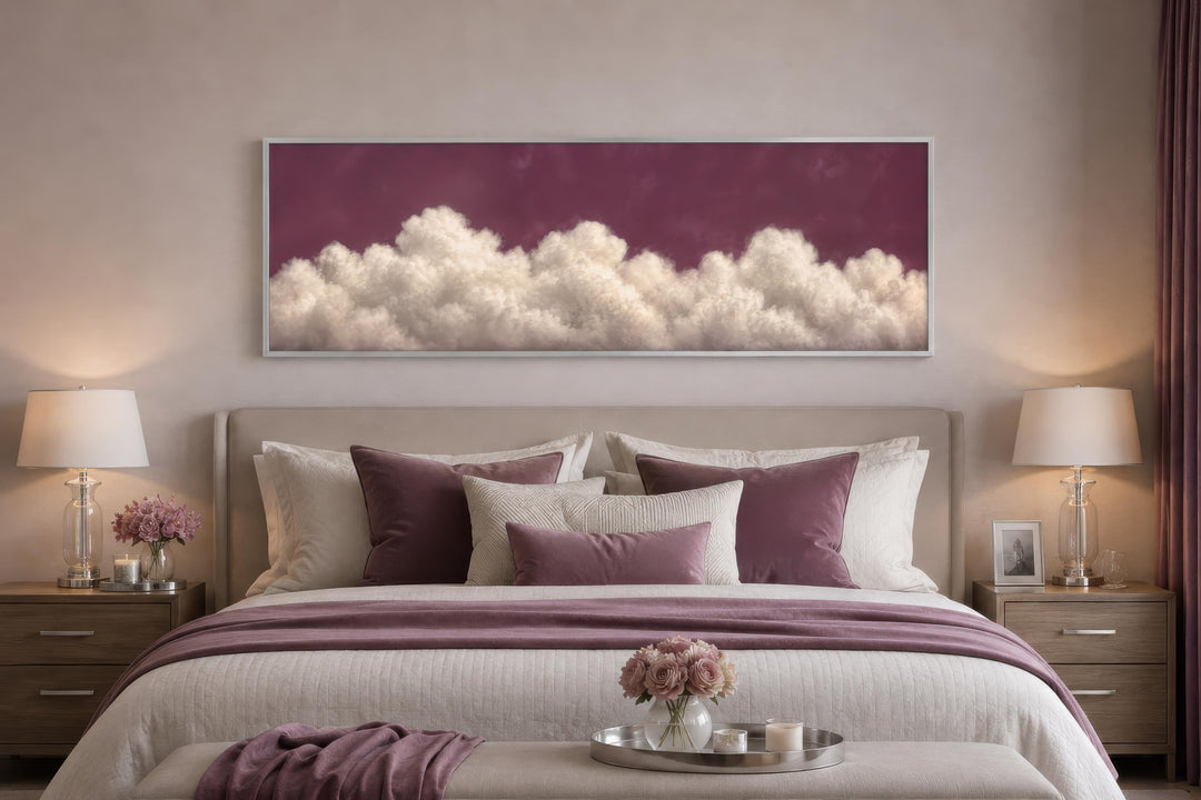 Long narrow canvas print of white fluffy clouds against a deep purple sky above a bedroom headboard.