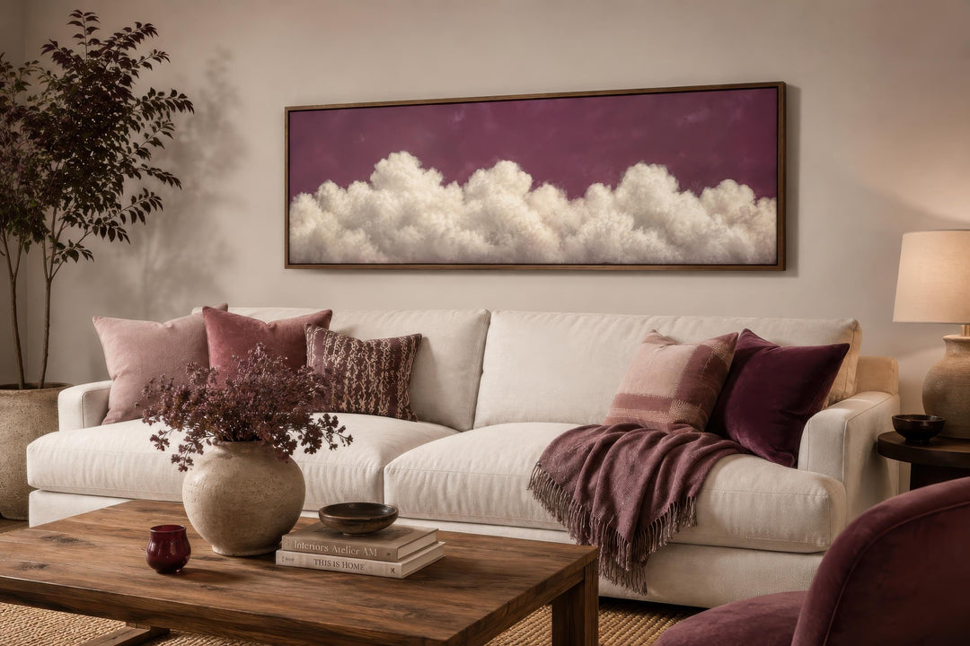 Long narrow canvas print of fluffy white clouds against a deep purple sky above a white sofa.