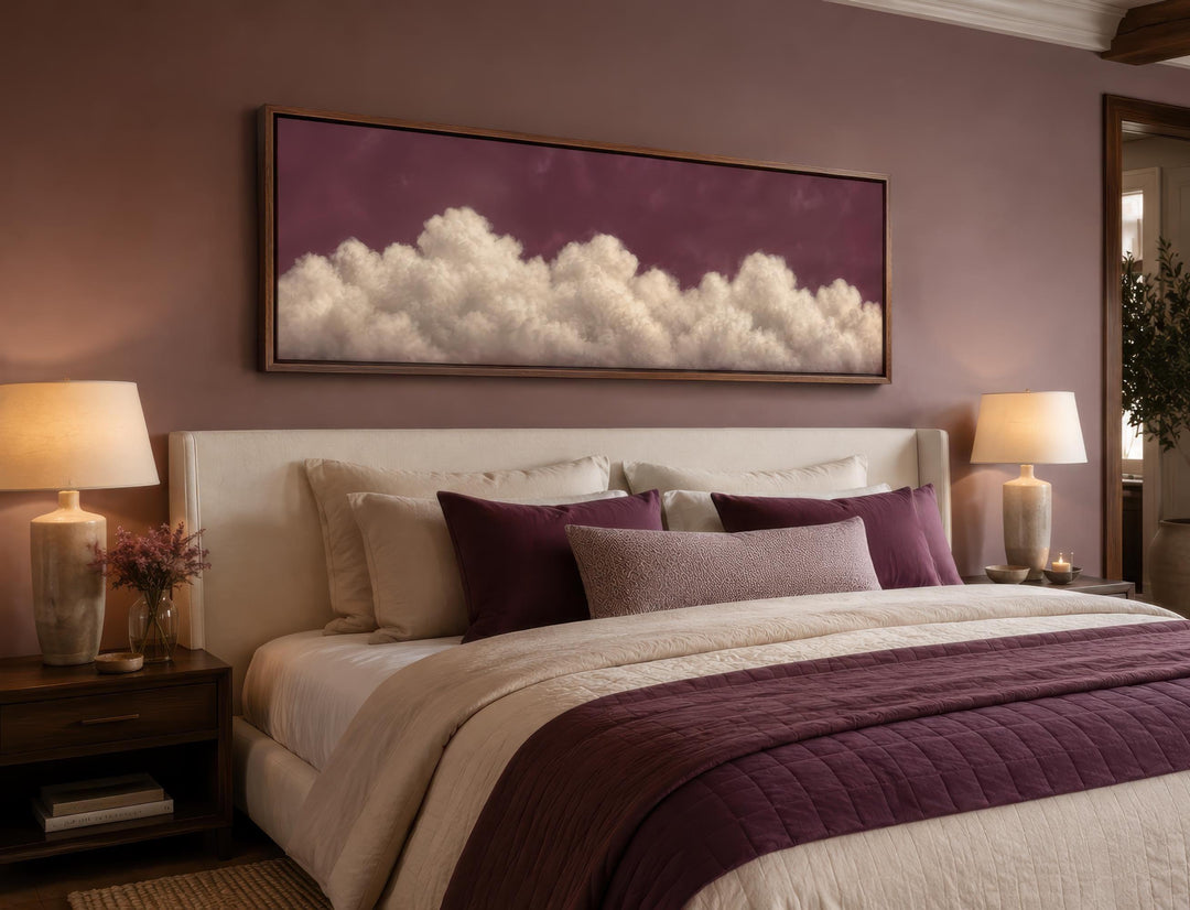 Long narrow canvas print of white fluffy clouds against a deep purple sky above a bedroom headboard.
