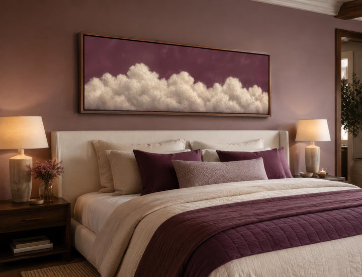 Long narrow canvas print of white fluffy clouds against a deep purple sky above a bedroom headboard.