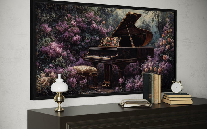 Framed canvas art of a grand piano in a lush purple floral garden above a dark wood console table.