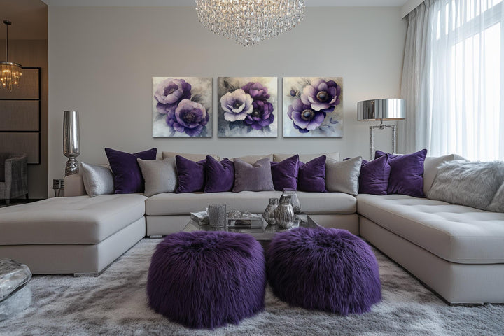 Set of three purple floral canvas prints displayed above a modern sofa in a living room.