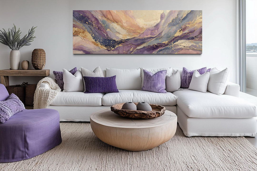 A long horizontal abstract canvas with purple and gold marble patterns hangs above a white sofa.