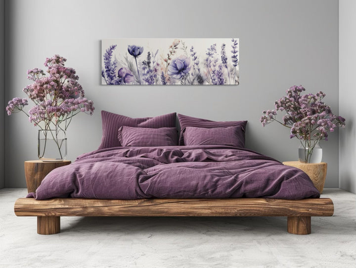 Panoramic framed canvas wall art of purple lavender wildflowers hanging above a bed.