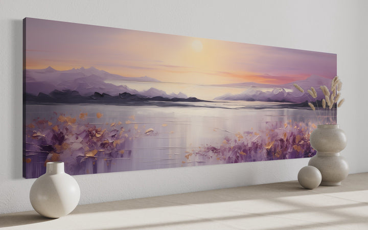 Long horizontal purple mountain lake sunset painting on a white wall with decorative vases.