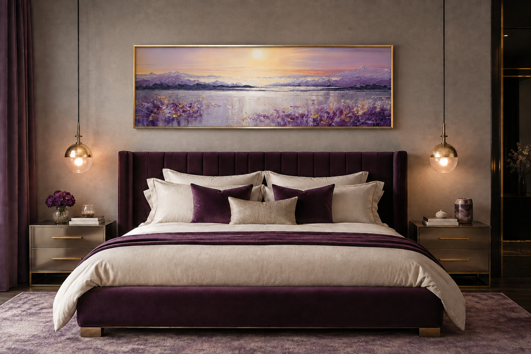 Purple mountain lake sunset painting in a gold frame hanging above a velvet bed.
