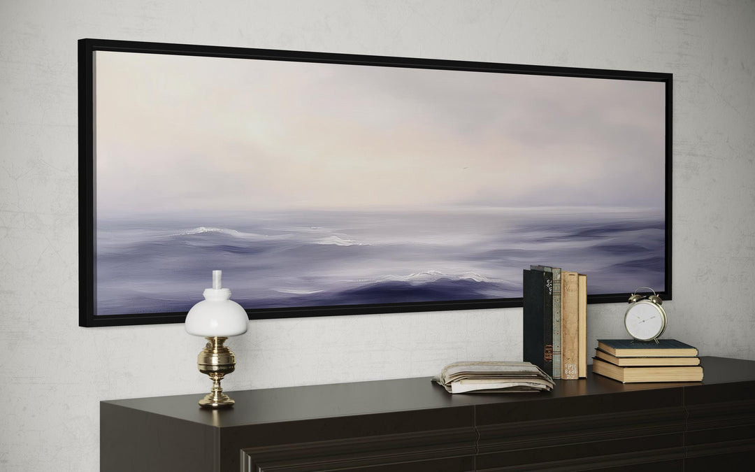 Purple Ocean Waves long horizontal coastal canvas wall art in a black frame above a dark dresser.