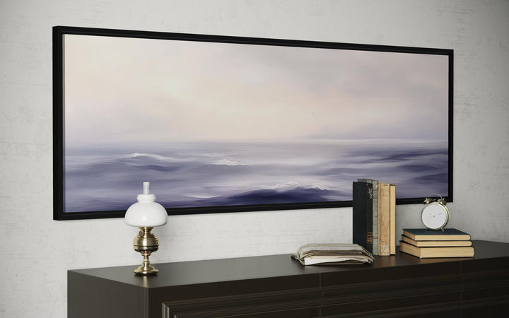 Purple Ocean Waves long horizontal coastal canvas wall art in a black frame above a dark dresser.