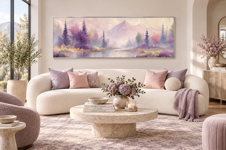 Long horizontal wall art of a purple lake landscape with mountains and trees above a white sofa.