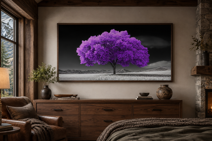 Framed canvas wall art of a vibrant purple tree against a black and white landscape in a bedroom.