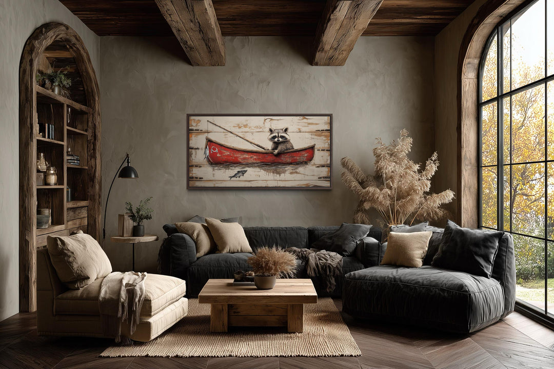 Whimsical raccoon fishing wall art in a red boat displayed in a rustic, cozy living room.